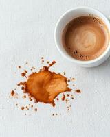 Coffee spill on white fabric with a full cup photo