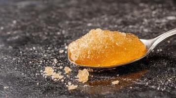 Spoonful of golden honey on a dark surface photo