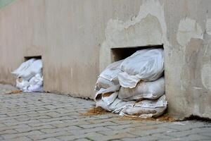 Sandbags stacked to air vents in building wall to prevent flooding photo