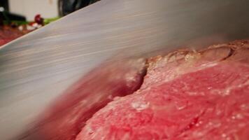 In a vibrant kitchen, a chef expertly cuts a large piece of fresh meat with a sharp knife. The atmosphere radiates a commitment to healthy, eco-friendly cooking techniques. video