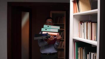 vertical A man holding a stack of binder folders in front of a bookcase video
