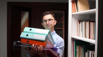 A man holding a stack of folders in front of a bookcase video