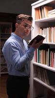 vertical A man in glasses is standing in front of a bookcase video