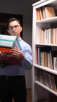 vertical A man holding a stack of binders in front of a bookcase video