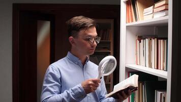Researcher is meticulously examining a book with a magnifying glass, standing by a bookshelf in a library, immersed in his studies and seeking specific information video