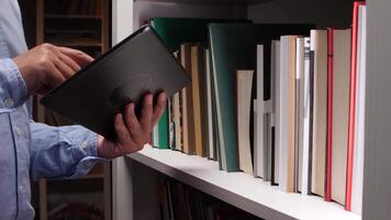 A person holding a tablet computer in front of a book shelf video