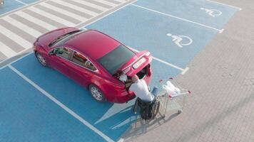 Side view of man unloading near red sedan video