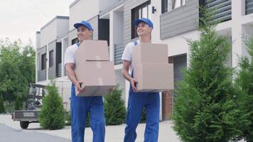 Rear view of deliverymen walking with boxes in suburban area video