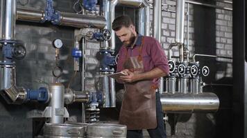 Man in apron adjusting controls in a brewery control station video