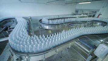 Filled PET bottles moving along curved conveyor in bottling plant. video