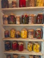 Preserved vegetables and fruits on display in glass jars in a kitchen photo