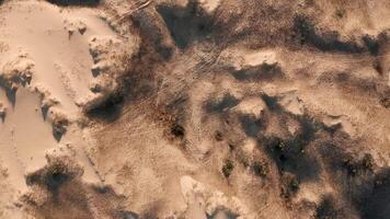 Aerial view of sandy terrain with dark patches and textured surface under sunlight. video