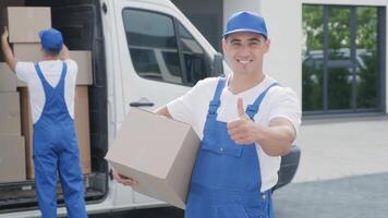 Two young workers of removal company are loading boxes and furniture into a minibus 2 video