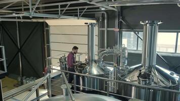 Technician adjusting controls near stainless brewing tanks video