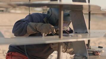 Focused engineer welding UAV frame during field testing on sand site. video