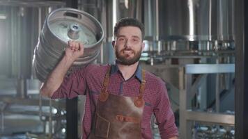 Man in apron presenting a keg in a modern brewery setting video