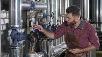 Brewer operating control valves on a fermentation tank in a modern brewery video