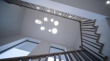 Elegant staircase with contrasting wooden steps and metal railings in a bright, high-ceilinged home with decorative hanging lights video