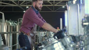 Technician regulating valve flow on a beer processing system video