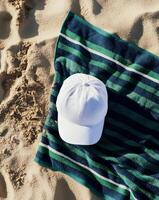 White Cap Resting on Striped Beach Towel Under Sunlight on Sandy Shore photo