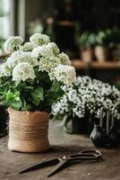 Floral Arrangement With White Blooms and Gardening Tools on a Rustic Wooden Table. photo
