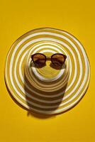 Stylish Sun Hat and Sunglasses Set on Vibrant Yellow Background for Summer Vibes photo
