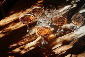 Elegant Cocktail Glasses Arranged on Wooden Table With Light Reflections in Cozy Indoor Setting photo