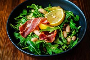 Fresh Arugula Salad With Lemon and Prosciutto on a Wooden Table photo