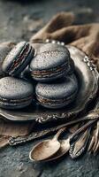 Elegant Black Macarons Arranged on a Vintage Silver Platter With Silverware on a Rustic Table. photo