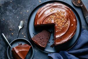 Chocolate Cake With Nuts Sliced on a Black Plate Accompanied by a Small Serving. photo