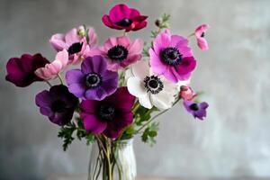 Colorful Anemone Flowers Arranged in a Clear Vase on a Wooden Table. photo