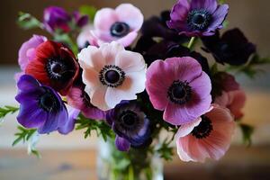 Colorful Bouquet of Anemone Flowers in a Glass Vase on a Wooden Table photo