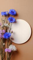 Cyan Flowers Arranged Next to a Blank Circular Card on a Smooth Surface. photo