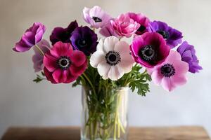 Colorful Anemone Flowers Arranged in a Clear Vase on a Wooden Table photo