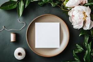 White Card on a Plate Surrounded by Flowers and Thread for Creative Projects and Invitations. photo