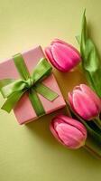 Pink Gift Box and Fresh Pink Tulips on a Green Background for Spring Celebrations and Special Occasions photo