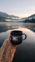 Enjoying a Warm Cup of Coffee by Tranquil Lake at Dawn. photo
