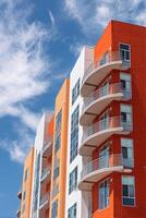 Modern Orange Apartment Building With Balconies Under Blue Sky and White Clouds photo