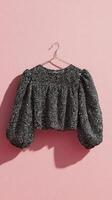 Unique Black and Silver Textured Crop Top Hanging Against Pink Background photo