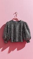 Unique Black and Silver Textured Crop Top Hanging Against Pink Background. photo