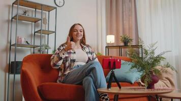 Pretty female girl blogger looks at device screen taking selfie on mobile cell phone cam, make virtual call online on modern social media vlog application. Woman with smartphone on sofa at home video