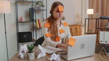 Exhausted woman freelancer with pasted sticker notes using laptop computer having concentration problem, creative crisis. Nervous adult girl confused by big routine work loading indoors at home office video