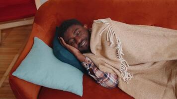Portrait of african american young man sleeping quietly in bedroom at home. Happy adult guy smiling, lying on bed, sleeping on a comfortable sofa and pillow, resting peacefully. Healthy sleep alone video