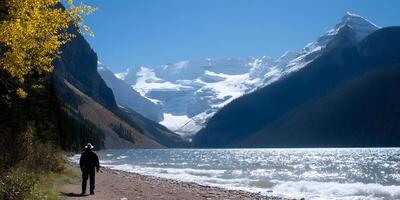 Man Hiking by Lake and Snowcapped Mountains Autumn Scenery photo