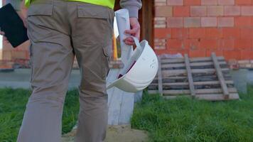 Real estate foreman designer building project architect. Professional civil engineer developer builder with helmet in hand walking to construction site. Constructor foreman. Start of working day video