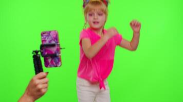 Young Blogger Concept. Cheerful teen school girl kid dancing at camera filming using phone at home on chroma key background, creating her trendy content on a mobile app to share on social media video
