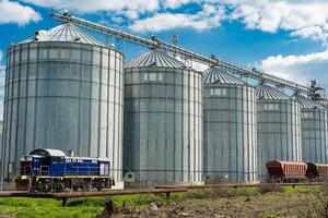 Agricultural silos for storage harvest at an agricultural production farm. Modern granary elevator. Loading and transportation of agricultural products by railway. Agribusiness photo