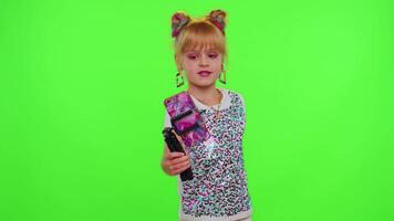 Funny little Caucasian kid girl blogger front of phone camera record enjoy dance content on green chroma key background. Social distance coronavirus pandemic concept. Freedom active lifestyle video