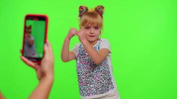 Happy funky young female blogger child kid girl, recording funny dancing on smartphone for social network or personal channel, having fun entertaining on weekend at home on chroma key background video