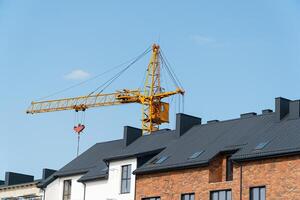 Modern beautiful houses. Modern construction. Yellow construction crane on the background of the sky photo